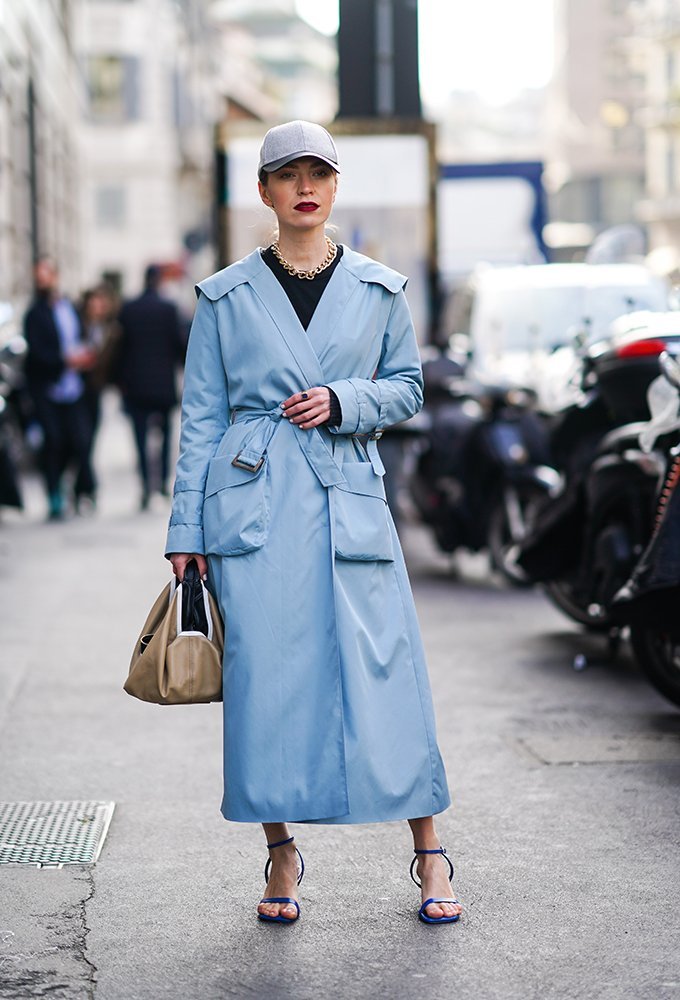 Mujer usando una gorra fitted con un largo trench azul