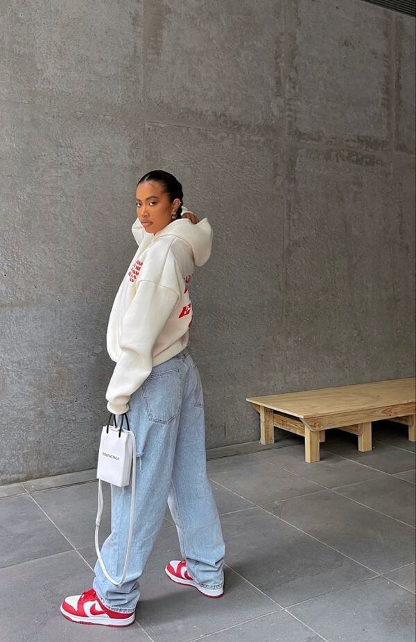 Mujer que lleva una sudadera blanca y un par de jeans boyfriend con zapatillas