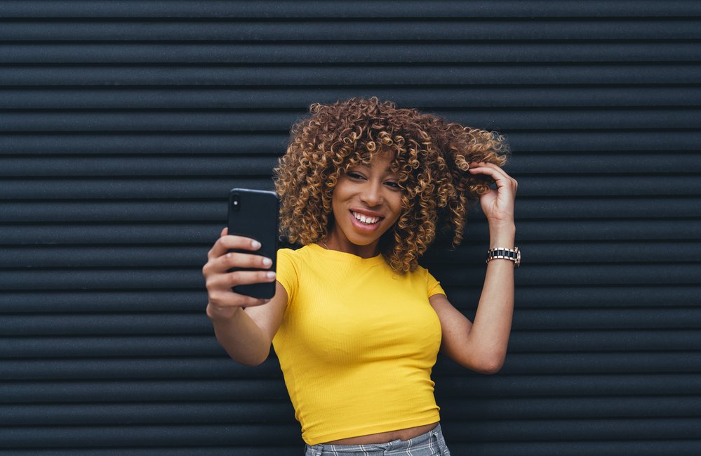 Mujer con blusa amarilla tomando un selfie