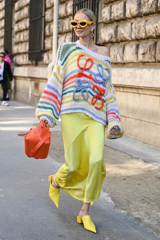 Mujer que lleva un bolso tejido encima de un vestido en la calle.